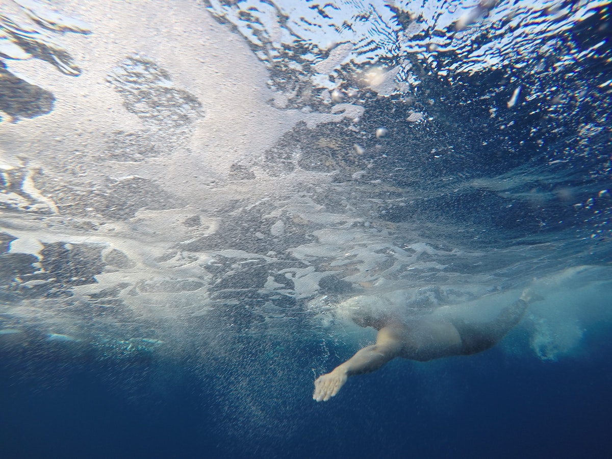 man swimming underwater in the ocean